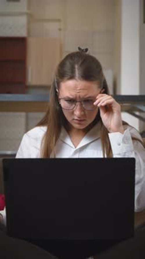 Geschäftsfrau passt die Brille an und reagiert schockiert auf den Laptop-Bildschirm