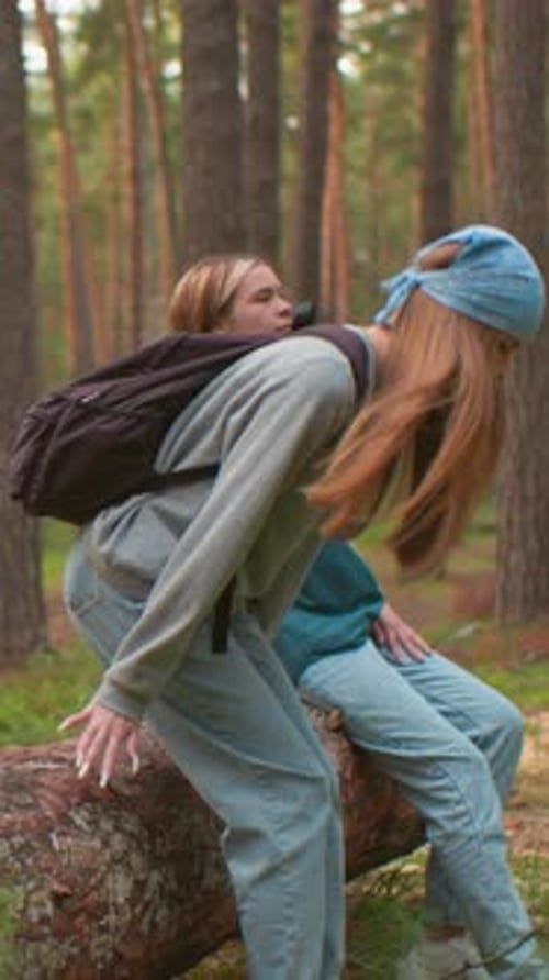 Two Tired Hikers Rest on Fallen Tree in Serene Forest