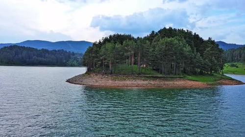 Lago con aguas cristalinas y costa de piedra en un bosque de abetos con abetos contra un cielo diurno