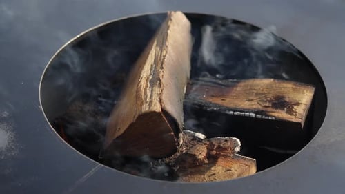 orbiting shot of smoke rising from the burning wooden logs for a bbq