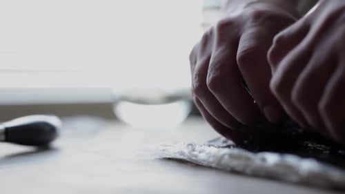 Hands Preparing Sushi Rolls with Rice and Fish