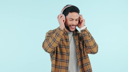 Headphones, music and happy man dance in studio isolated on a blue background mockup space