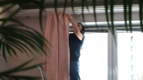 Woman Hanging Window Curtain Indoors