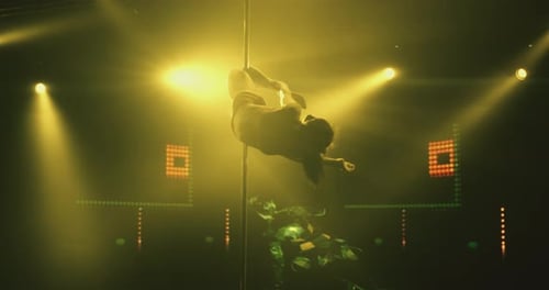 Flexible Woman Doing Pole Acrobatics in Yellow Light