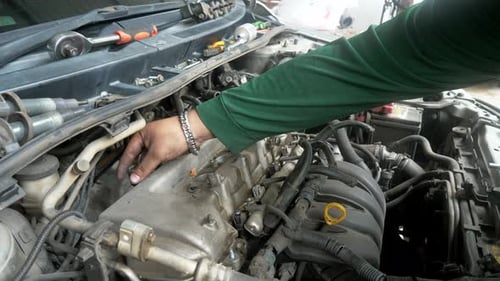 A closer look at a mechanic unscrewing some parts of the car's engine to repair it in a shop in Bang
