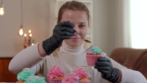 Woman Decorating Cupcakes with Sprinkles in Home Setting