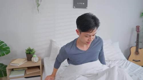 Man Wakes Up and Stretches in Bed