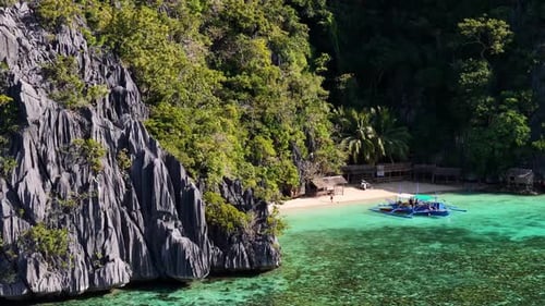 Aerial drone shot of a resort made on a beach in coron with a boat parked near it.
