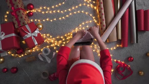 Woman Wrapping Christmas Gifts on Lit Floor