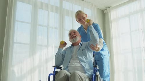 Senior Man in Wheelchair Does Exercises with Nurse