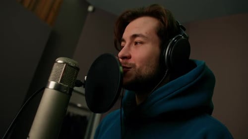 singer with headphones and microphone emotionally recording a new song in a professional studio
