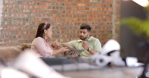 Discuter des détails du projet, collègues utilisant une tablette assis sur le canapé du bureau