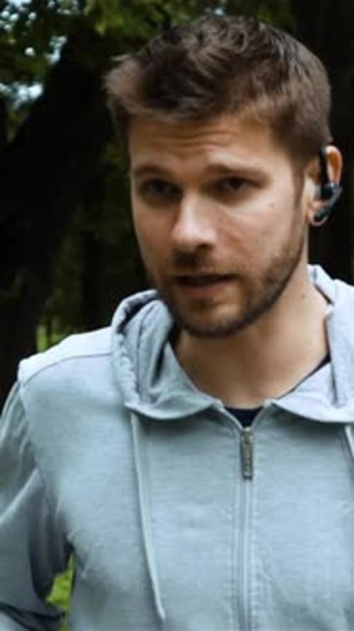 Vertical of Road Runner Man Talking By Phone with Bluetooth Headset