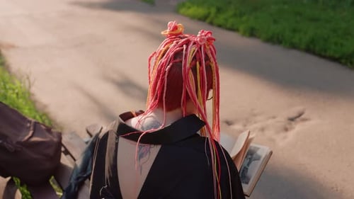 Young Woman with Braids Reads Book in Park