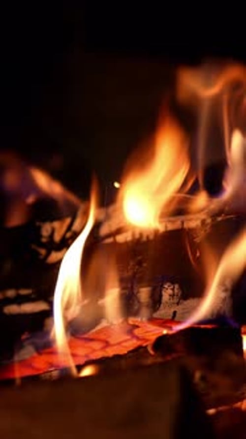 Cropped view of the wood burning in a fireplace during the night. Warm cozy fire in a fireplace.