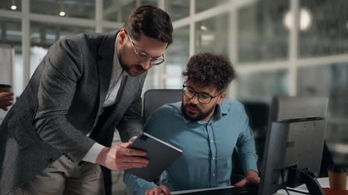 Two Multiethnic Business Colleagues Men Businessmen Talking Comparing Data in Digital Tablet Compare