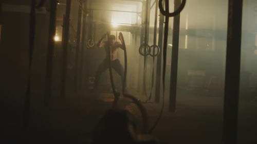 Man Exercising with Battle Ropes in Gym