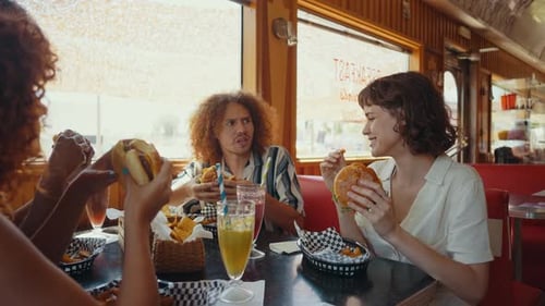 group of multi-ethnic friends eating and having fun in an american styled diner restaurant.