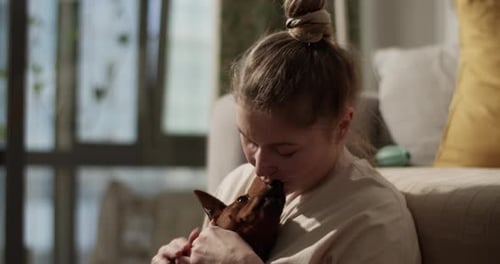 Woman Cuddling Small Dog at Home
