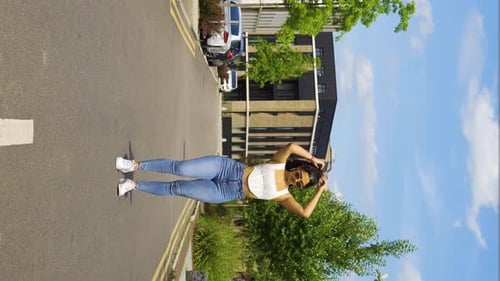 cool vibe girl woman in the middle of the street fixing touching hair tight jeans performing afro da