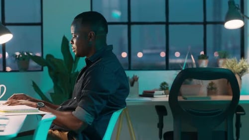 Homme noir, ordinateur et travail de nuit au bureau d'une start-up, dactylographie et communication pour le marketing