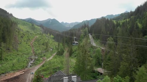 drone shot following a cable car going up in the mountains