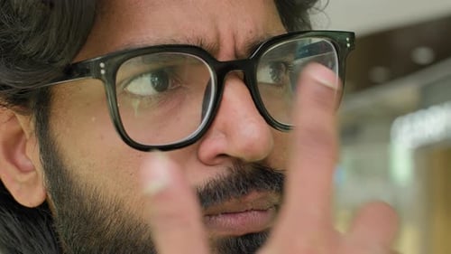 Extreme Nahaufnahme männlicher Augen mit Brille indischer nachdenklicher Mann, der die richtige Brille anpasst