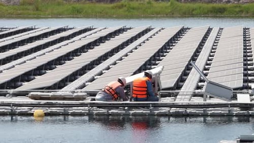Schwimmendes Solarpanel auf dem Teich. Der Arbeiter wartet und überprüft schwimmende Photovoltaikmodule.