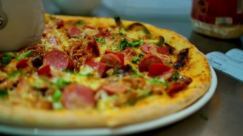 A pizza with a lot of toppings getting cut by a pizza cutter in slow motion, close up