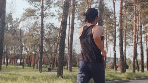 Young Sportsman in a Black Sportswear Running on an Alley in an Autumn City Park on a Sunny Day Back
