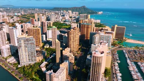 Architecture of modern Waikiki lit with bright sun. Diamond Head Crater at backdrop. Aerial view.