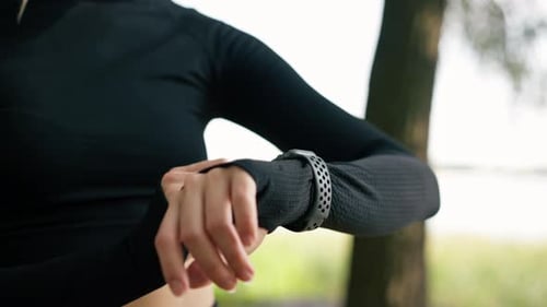 Close-up of a girl looking at the sports watch on her hand to determine number of kilometers she run
