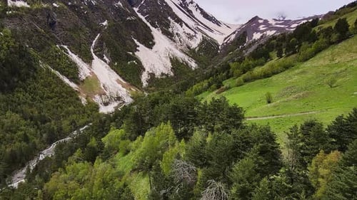 Breathtaking Aerial View of Snowtopped Peaks and Green Valley with River