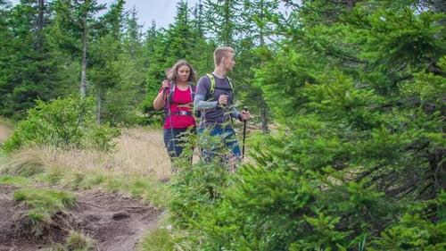 Two people hiking on a mountain carrying hiking equipment.