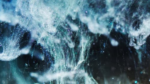 Close-up of vibrant blue and white ink dispersing in water, creating an abstract visual effect
