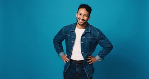Happy man, face and fashion with confidence in studio for denim outfit on a blue background
