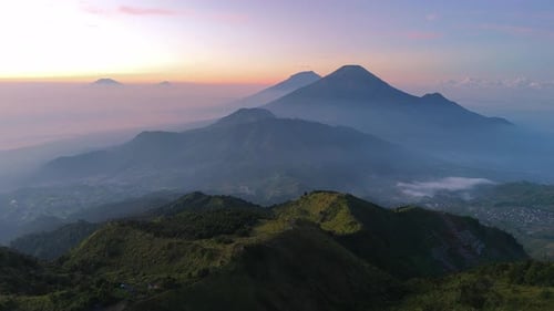 Aerial scenery of mountainous region with dramatic layered hills, mountain peak and sunrise sky