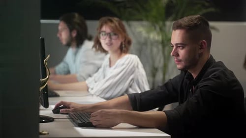 Junger Geschäftsmann diskutiert mit Kollegen über Desktop-PC im Büro