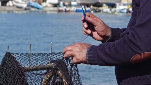Hands Of Old Man Weaving Fishing Net For Fishery Equipment At Marina