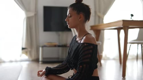Young Woman Meditates in Sunny Home Living Room