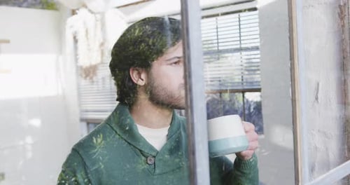 Thoughtful Person Drinks from Mug near Window