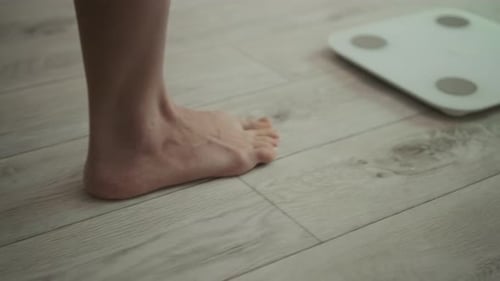 Legs of Young Girl Standing on Scale to Measure Weight