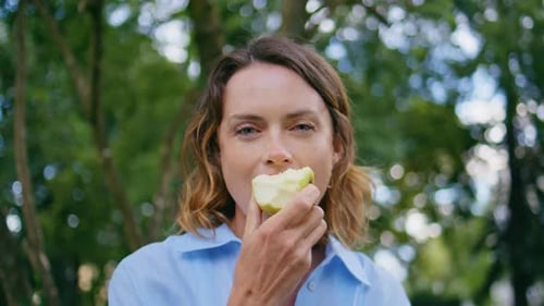 Happy Woman Eating Fruit at Park Portrait Lady Enjoying Apple Looking Camera