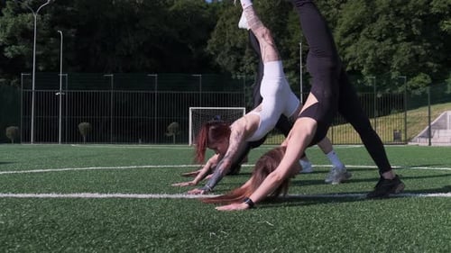 Women Practicing Yoga Outdoors on Green Athletic Field
