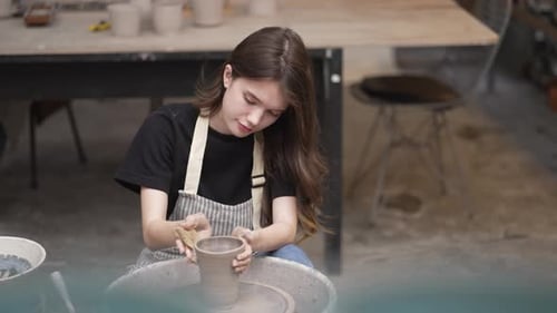 Young women is making earthenware at workshop.
