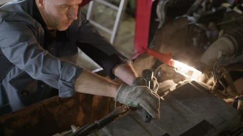 Man Fixing Car Engine in Garage With Wrench