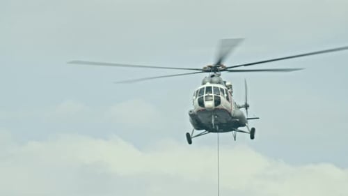 Helicopter flying in cloudy sky with rotating blades