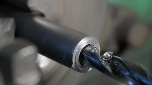 Drilling detail on lathe with metal shavings.
