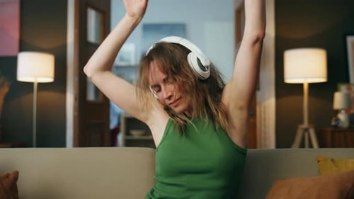 Excited Woman Dancing to Music on Couch