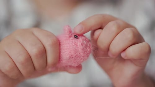Mädchen spielt mit kleinen gestrickten Tierspielzeugen in einem Zimmer zu Hause